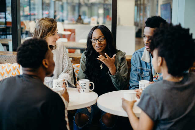 diverse group of young adults having a conversation at a cafe