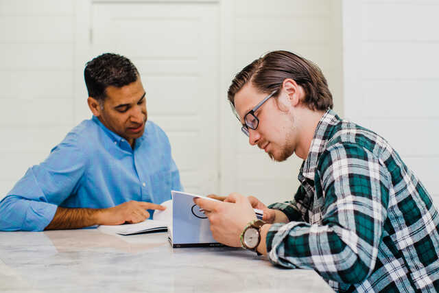 two men having a mentoring conversation over a workbook
