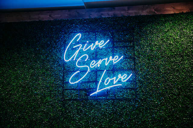 neon sign that says give serve love