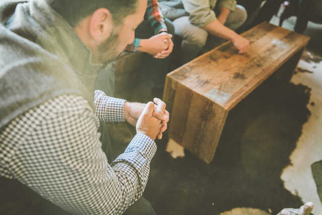 group of men praying in a living room